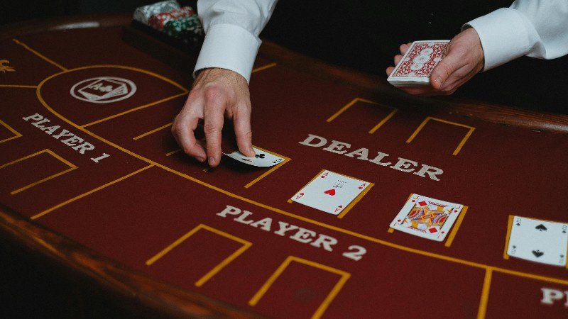 A casino dealer distributes playing cards at a poker table, ready for a game. - pexel