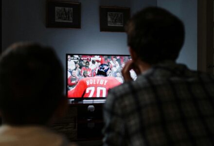 Father and son enjoying a hockey game together on TV from their living room., tags: nhl prop bets - pexel