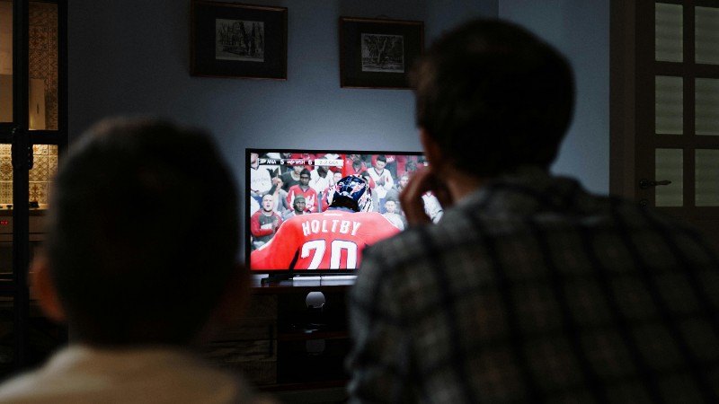 Father and son enjoying a hockey game together on TV from their living room., tags: nhl prop bets - pexel