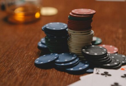 Poker chips stacked on a wooden table with playing cards and blurred glass in the background., tags: ontario’s - pexel