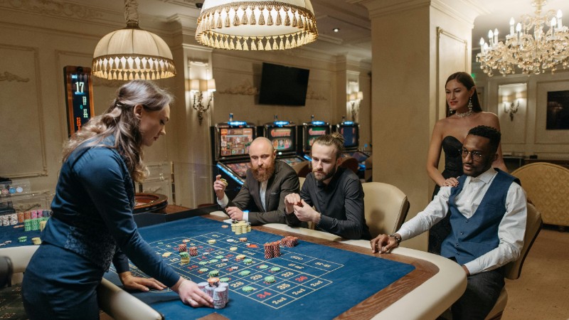 A diverse group of adults enjoying a night at the casino, playing roulette indoors., tags: canadian - pexel