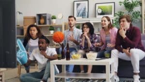 Group of friends excitedly watching a sports game indoors, enjoying snacks., tags: betting - pexel