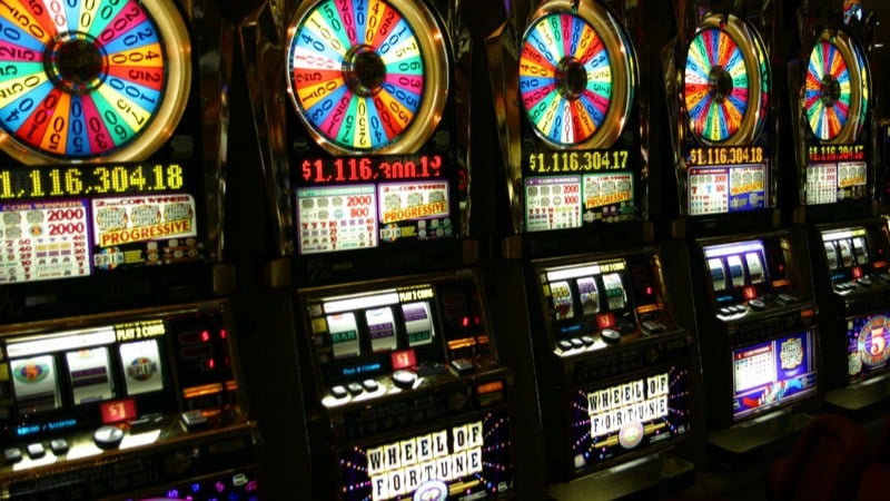 A row of ' Wheel of Fortune' slot machines in a casino in Las Vegas. This specific slot machine is themed to the TV game show Wheel of Fortune., tags: bet, spin, fun money - CC BY-SA