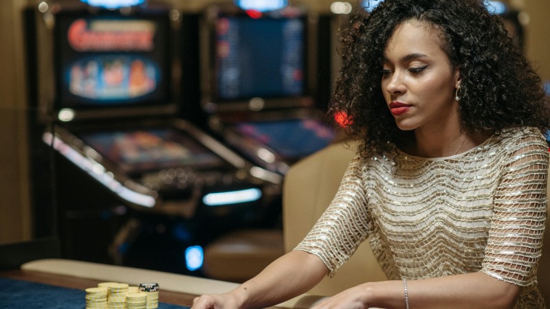 Elegant African American woman betting at casino gaming table with chips., tags: playtech guide - pexel