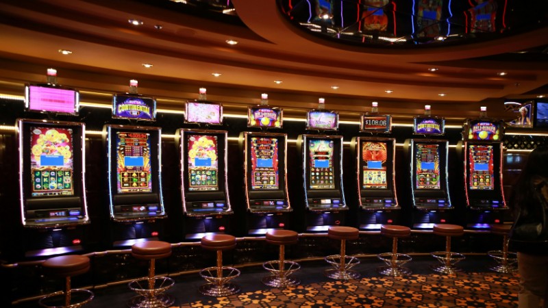A row of luxury slot machines in a casino interior with plush stools, perfect for gaming enthusiasts., tags: money slots - pexel
