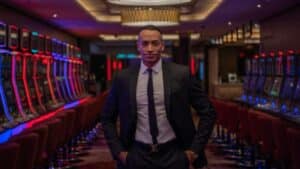 Businessman standing confidently in a luxurious casino with rows of gaming machines., tags: playtech fun, - pexel
