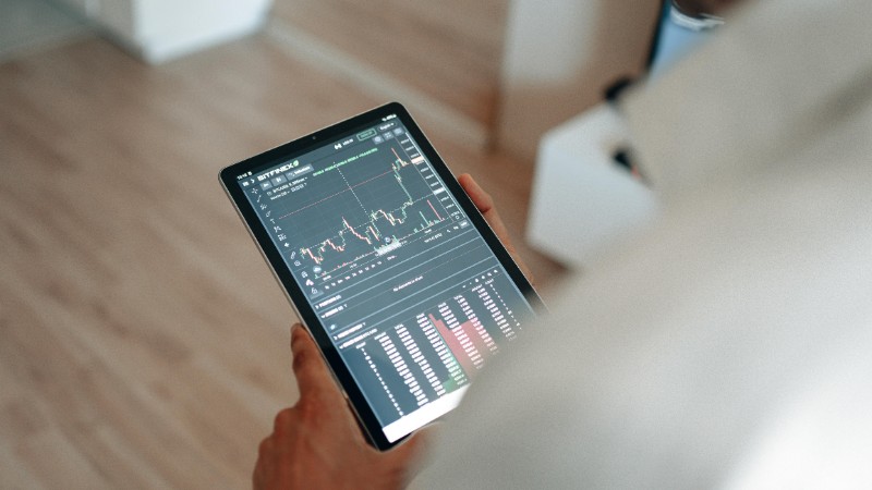 Close-up of person using a tablet displaying trading graphs indoors., tags: gambling - pexel
